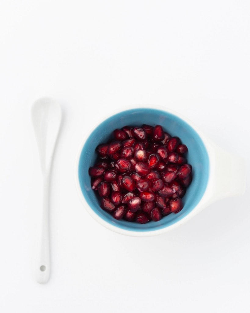 Granaatappelpitten in een blauw schaaltje naast een lepel