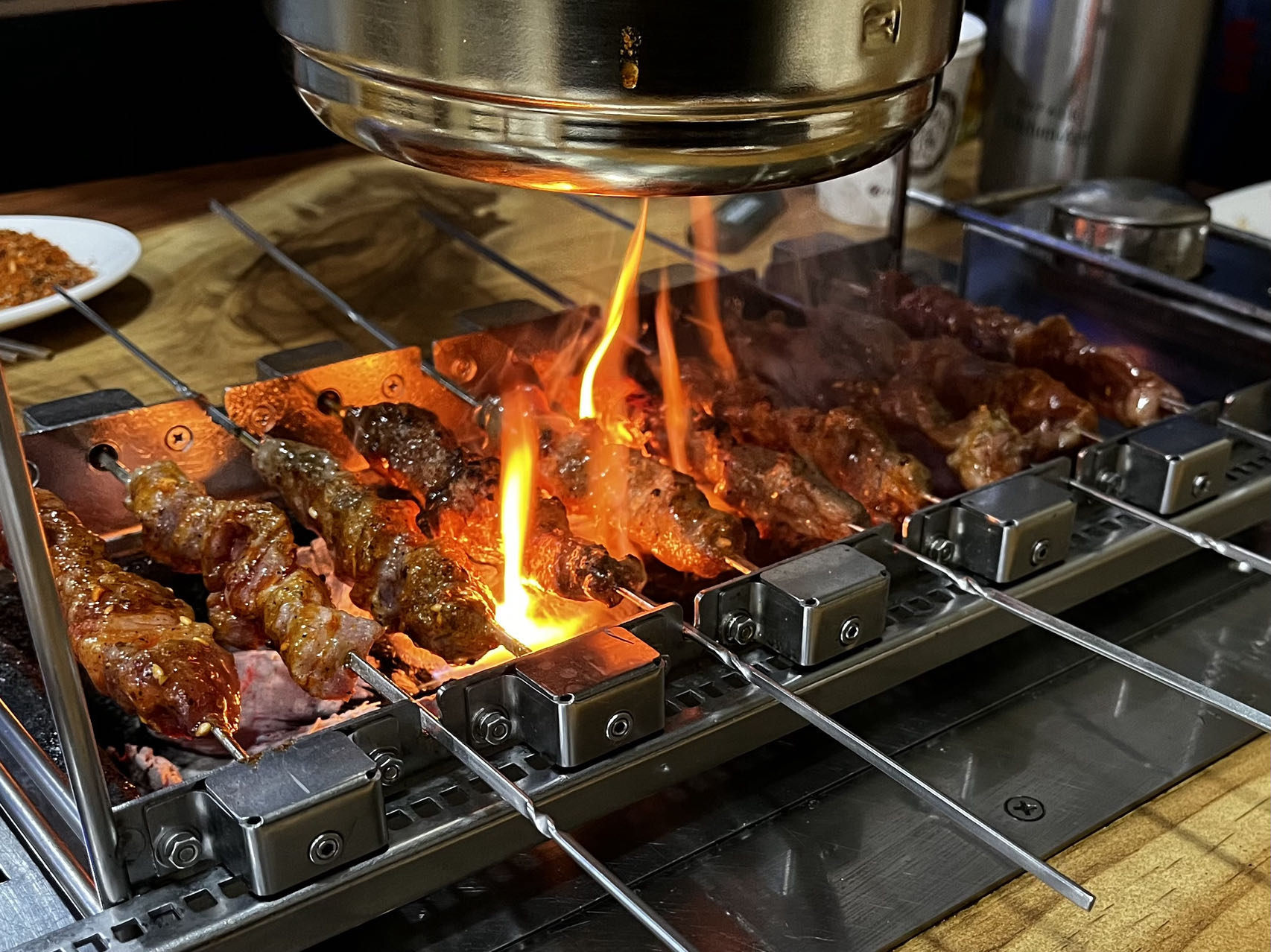 Vleesspiesen boven de vlammen van een houtskoolgrill
